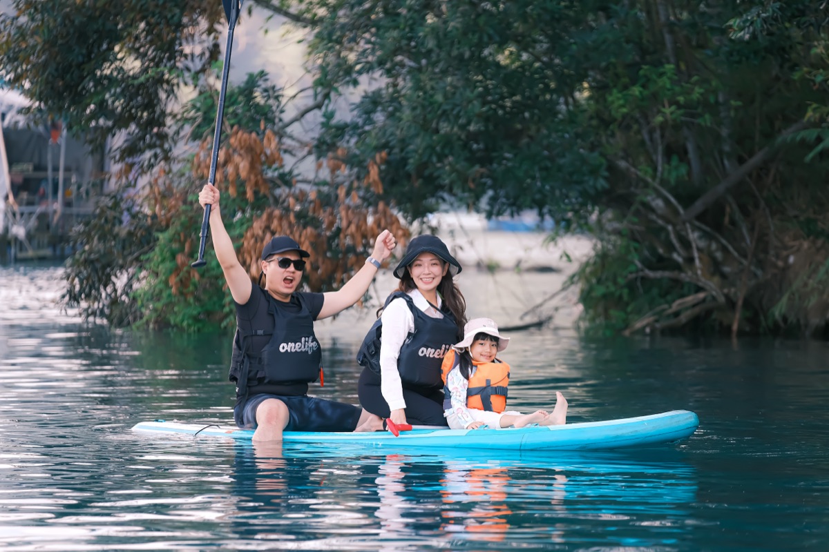 Happy family of three enjoying SUP paddleboarding on Sun Moon Lake